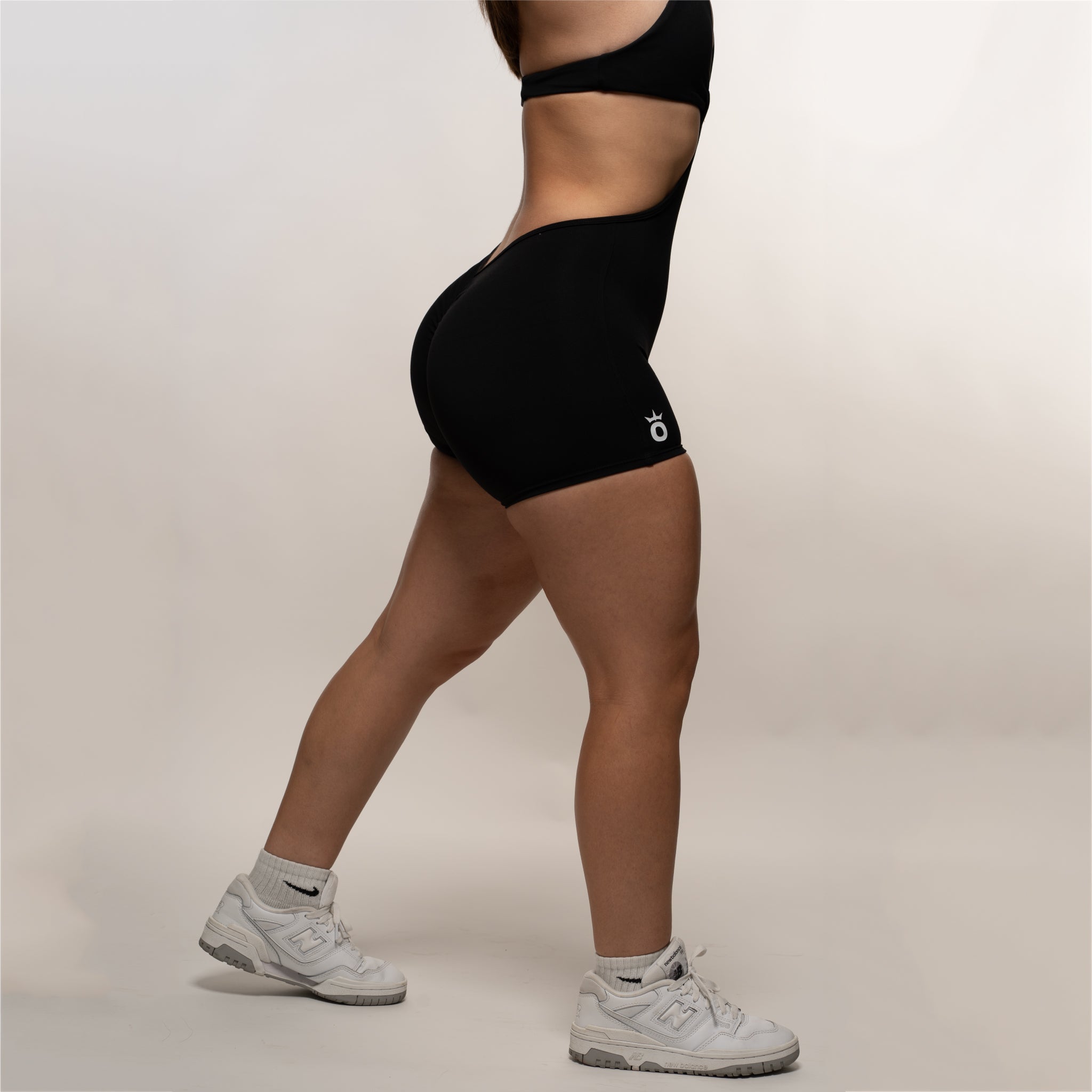 A woman wearing black Crush Bodysuit Shorts, the ultimate summer outfit staple.
